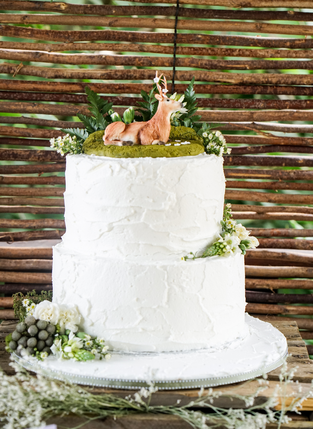 Enchanted Woodland Party Birthday Cake covered with buttercream and a fondant deer resting on top with some green moss